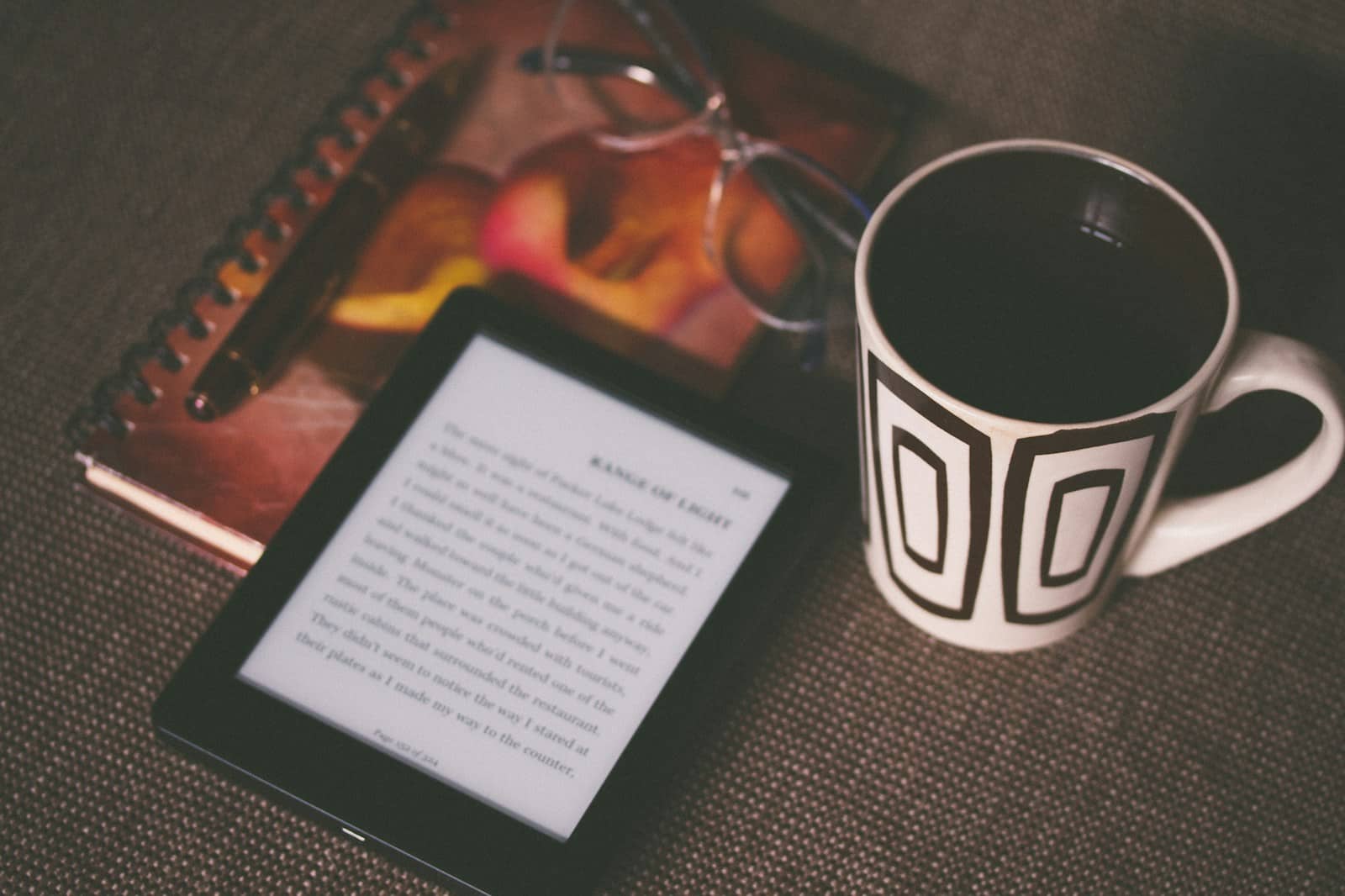 black E-book reader beside white and black mug kindle direct publishing